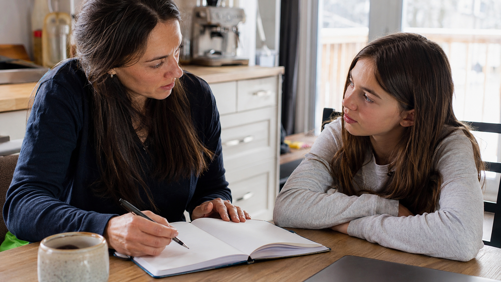 Un parent discute calmement d'une transition scolaire avec un enfant et note deux délais dans un agenda.